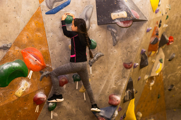 Malá holčička volné lezení na umělé stěně v tělocvičně, bouldering. - Fotografie, Obrázek