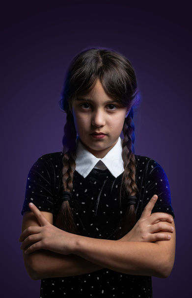 Retrato de niña con traje de miércoles Addams durante Halloween. Expresión seria y atmósfera oscura con fondo oscuro - Foto, Imagen
