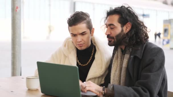 Slow motion video of a gay couple using a laptop sitting in a cafeteria - Video
