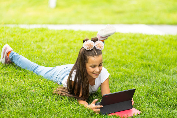 Cute little girl tablet PC in the park. - Photo, Image