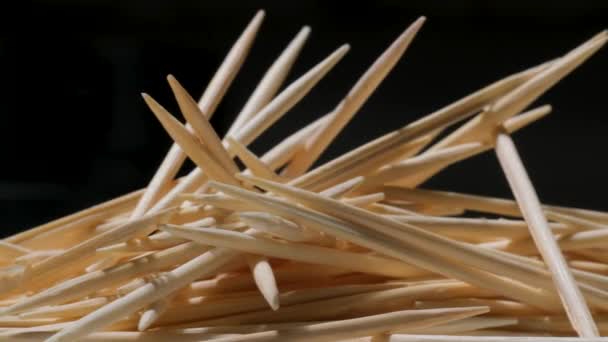 A pile of wooden toothpicks on a black background. Macro. Texture. Movement in a circle - Felvétel, videó