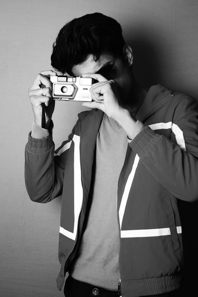 young boy wearing jacket and black glass with camera, looking in camera black and white image - Foto, afbeelding