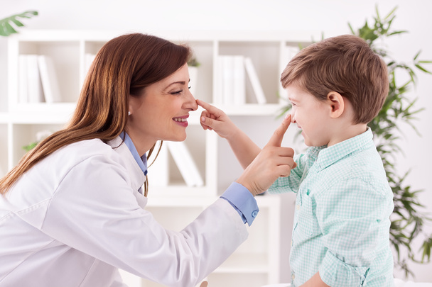 Lekarz i dziecko cieszyć się i grać razem dotykając nosa - Zdjęcie, obraz