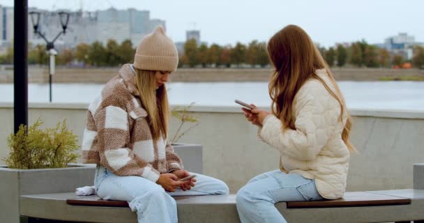 Trust and understanding between generations - mom and daughter spending free time together outdoor, using smart phones looking at the screen of a smartphones sharing photo, showing content. 4k footage - Séquence, vidéo