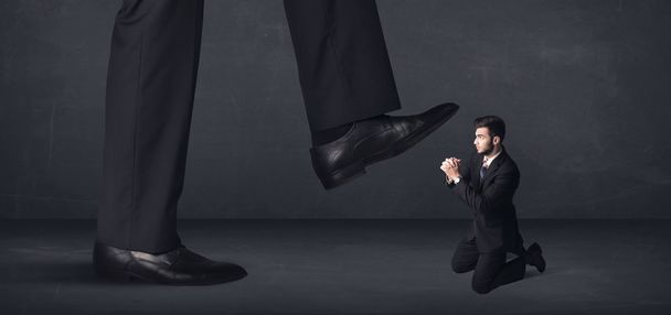 Giant person stepping on a little businessman concept - Foto, imagen