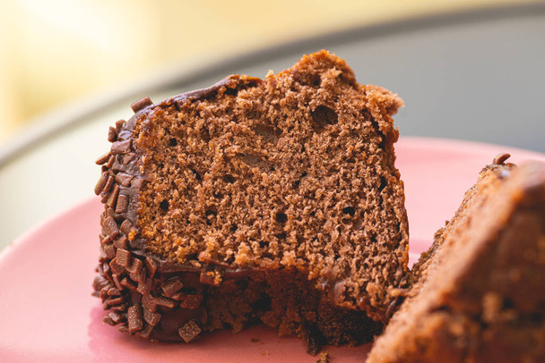 Шоколадний торт з вершковим шоколадним соусом і прикрашений шоколадними зморшками на рожевій тарілці. Шматочок торта
. - Фото, зображення