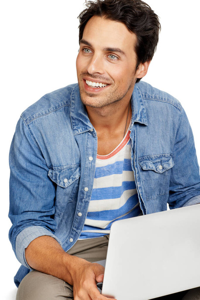 Checking my email in comfort. A handsome young man working on his laptop against a while background - Foto, imagen