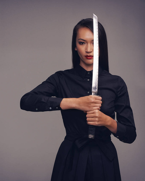 Portrait, samurai and warrior with an asian woman in studio on a gray background for martial arts or combat. Training, fantasy and weapon with a model ninja ready to defend using self discipline. - Foto, imagen