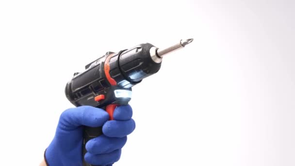 Close-up of an electric drill on a white background. The builder is holding an electric drill on camera. Apartment renovation concept - Materiał filmowy, wideo