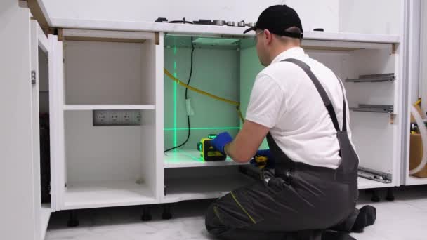 A worker installs furniture in the kitchen. The master uses an electronic laser. Repair in a new building - Video