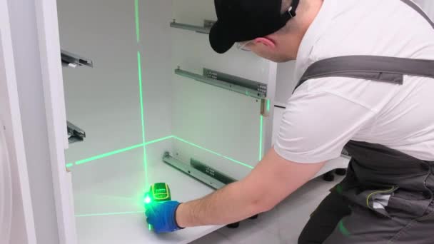 Installation of kitchen accessories using a construction laser. Professional worker. 4k video - Imágenes, Vídeo