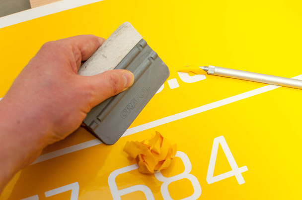 Крупный план руки мужчины, делающего наклейку на машину из желтой фольги - Фото, изображение