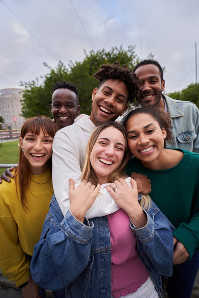 Vertical selfie of Young people embrace posing for a group portrait looking at the camera outside. Smiling friends of the millennial generation. Young guys and girls having fun together - Foto, afbeelding