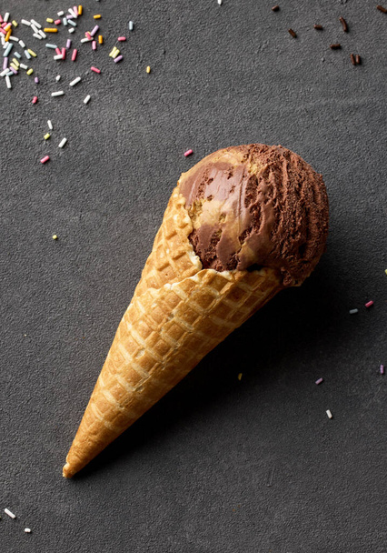 caramel and chocolate ice cream in waffle cone on dark grey background, top view - Foto, imagen
