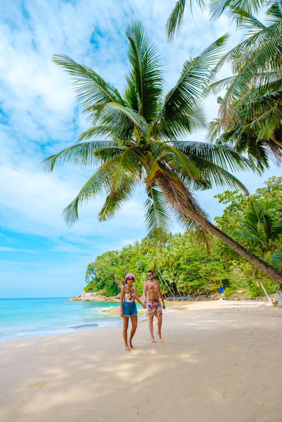 A couple of men and women walking on a white tropical beach with palm trees in Phuket Thailand. Surin Beach phuket - Foto, Imagem