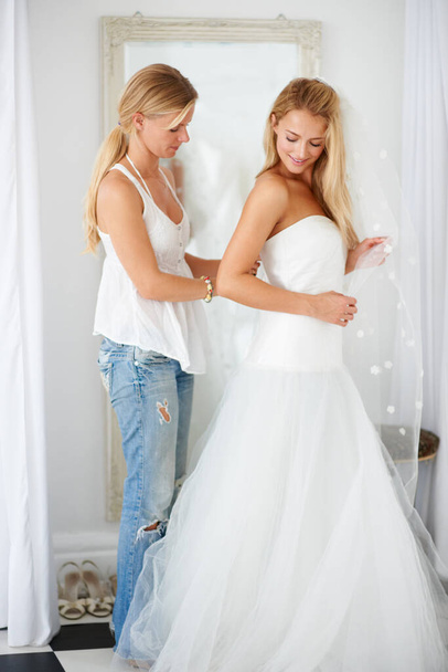 Starting to get excited for her big day. A young bride being helped into her wedding dress - Photo, image