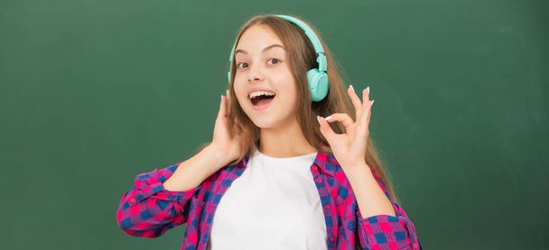 весела дитина слухає музику в навушниках на дошці, електронна книга
. - Фото, зображення