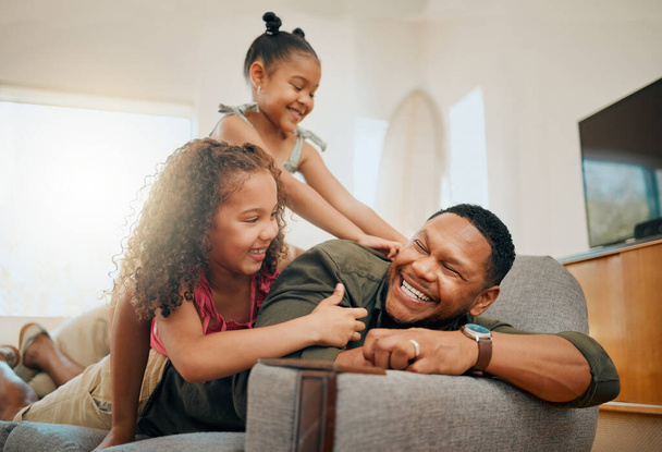 A happy mixed race family of three relaxing in the lounge and being playful together. Loving black single parent bonding with his daughters while playing fun games on the sofa at home. - Foto, immagini