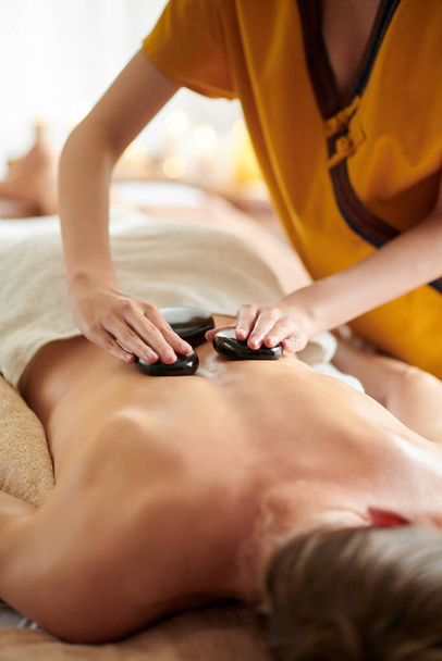 Обрізане зображення жінки, що отримує кам'яний масаж в спа-салоні
 - Фото, зображення