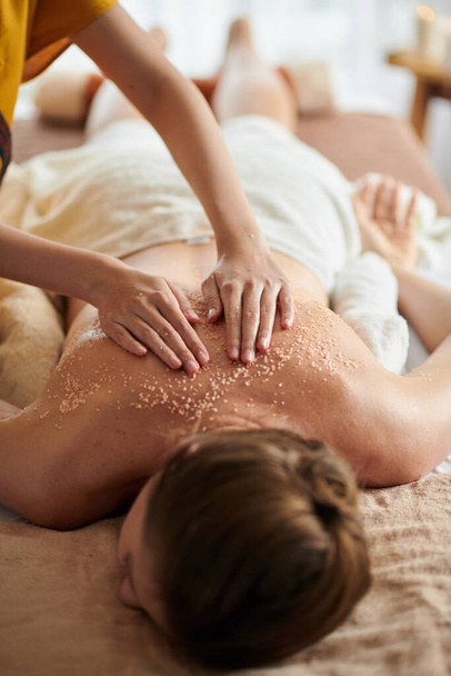 Woman getting deluxe spa treatment including warm seed oil and sea salt scrub - Foto, Imagen