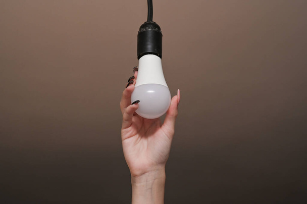 LEDランプの設置。省エネ。女性の手の電球には - 写真・画像