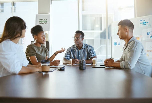 Group of diverse businesspeople having a meeting in an office at work. Happy african american businesswoman talking during a workshop at a table with coworkers. Businesspeople planning together. - Zdjęcie, obraz
