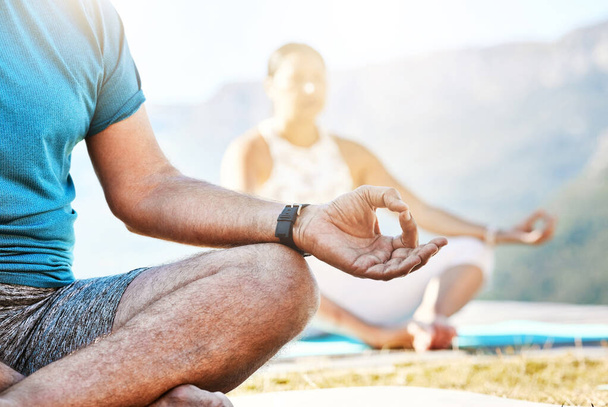 Close up of a senior man and woman sitting in lotus position and practising meditation during yoga exercise in nature and feeling calm. Retirees living healthy active lifestyle. - Foto, immagini