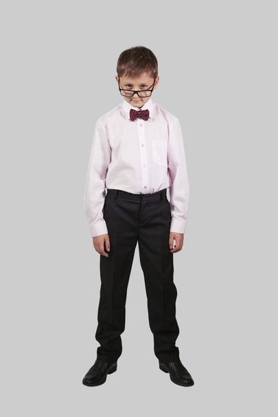 growth portrait of a boy in a bow tie that looks over his glasse - Photo, image