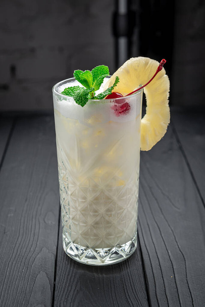 Glass with pina colada on dark background. Alcoholic cocktail - Φωτογραφία, εικόνα