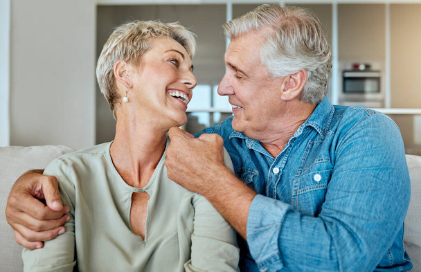 Una pareja jubilada feliz y relajada hablando y riendo juntos en la sala de estar. Sonriente pareja caucásica uniéndose en el sofá en casa. - Foto, imagen