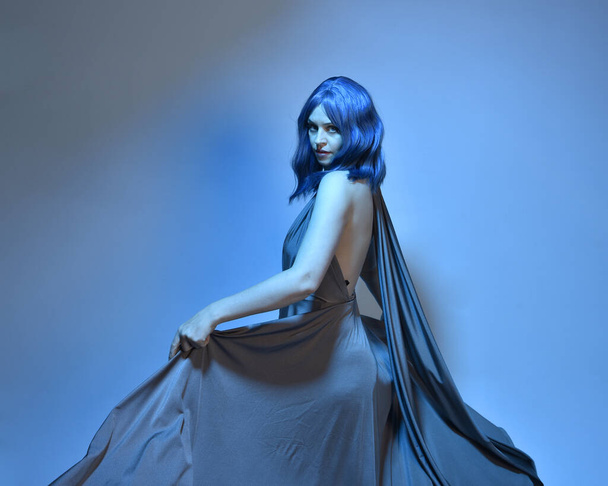 Портрет красивой девушки с голубыми волосами, жестикулярная поза руки тянется к красочному источнику света. красочный неоновый гель освещения, изолированные на фоне студии. - Фото, изображение