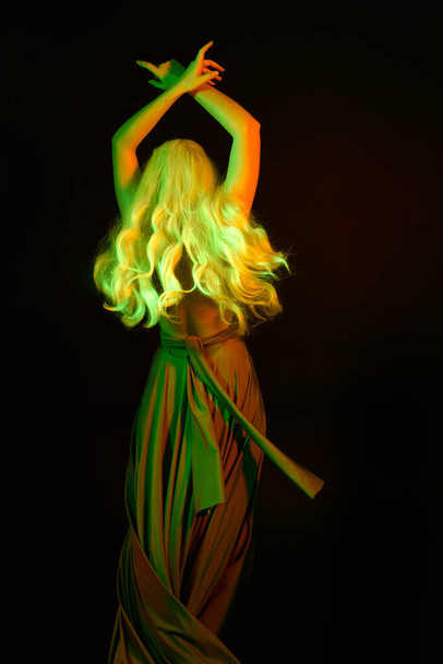 portrait of pretty girl with blonde hair & elegant gown with expressive facial expressions & gestural arm poses. colourful neon gel lighting, isolated on black studio background. - Fotoğraf, Görsel