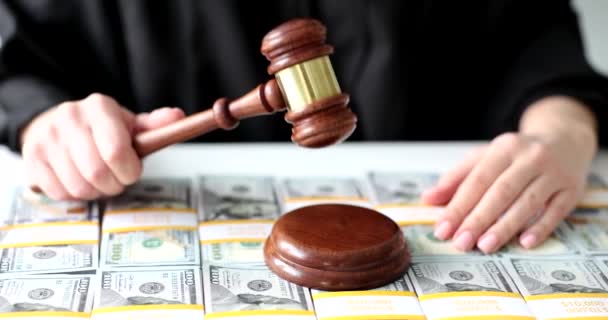 Judge knocks with wooden gavel and dollar bills. Financial crimes bribery and bribery of judge concept - Materiał filmowy, wideo