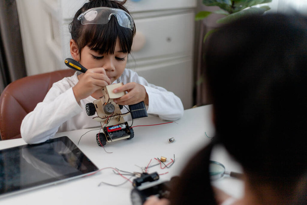 Aziëstudenten leren thuis in het coderen van robotauto 's en elektronische kartonnen kabels in STEM, STEAM, wiskunde engineering science technology computer code in robotica voor kinderen concept. - Foto, afbeelding