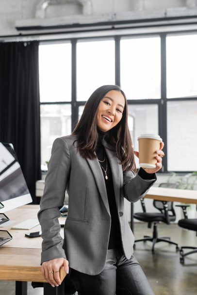 Усміхнений азіатський дизайнер інтер'єру тримає каву, щоб піти в офіс
  - Фото, зображення