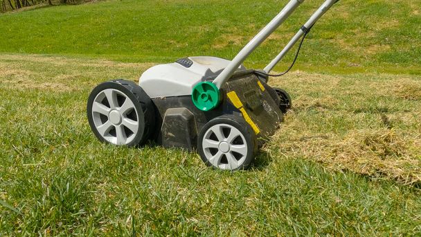 CLOSE UP: Grass aeration for soil compaction relief and grass growth enhancement. Spring backyard garden work for healthier and thicker lawn. Useful gardening machinery for efficiency at landscaping. - Photo, Image