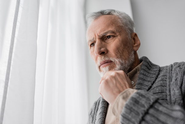 アルツハイマー病による記憶喪失に苦しむ緊張した男が自宅で顎の近くに立って - 写真・画像