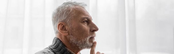 自宅でバナーを考えながら顎に触れるアルツハイマー病の老人のプロフィール - 写真・画像