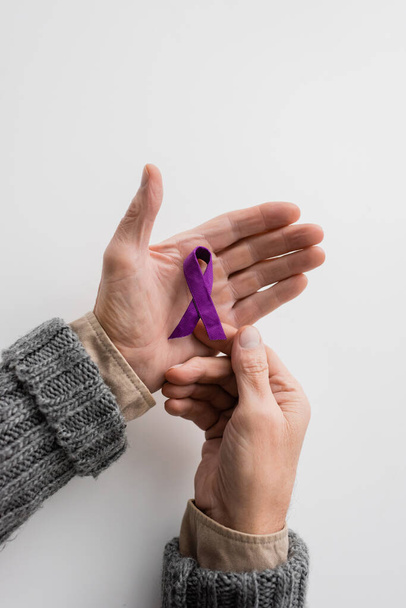 top view of cropped senior man with alzheimer disease holding purple awareness ribbon on white background - Foto, Imagem