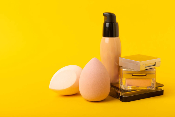 Beauty blender and tannal cream, concealer and shadows on a yellow background. Bright sponges for cosmetics. Makeup products. Beauty concept. Place for text. Place to copy. flat lay - Foto, Imagen