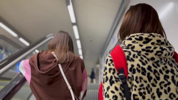 Mother and daughter on the escalators in a subway station, back view - Filmati, video