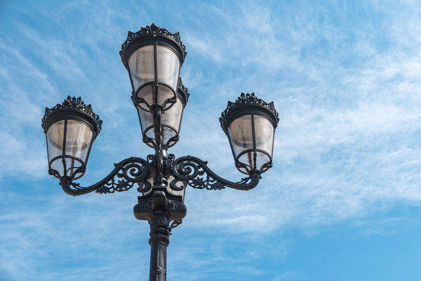 Old and vintage design street lamp bulb in Portugal with blue sky background. Building illumination. Retro lantern lighting - Fotó, kép