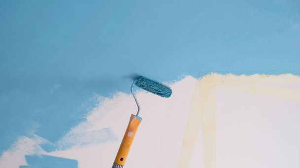 Розфарбуйте валик на стіну синім кольором, простір для копіювання білого тексту. Покращення будинку та концепція реконструкції
. - Фото, зображення