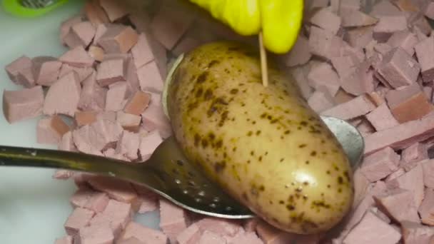 the cook's hand checks with a toothpick a boiled potato in a peel over a boiled sliced sausage. - Séquence, vidéo
