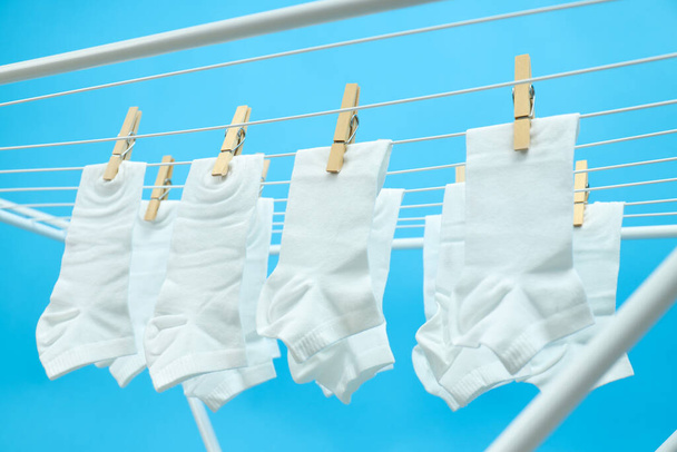 Meias brancas penduradas no rack de secagem no fundo azul - Foto, Imagem