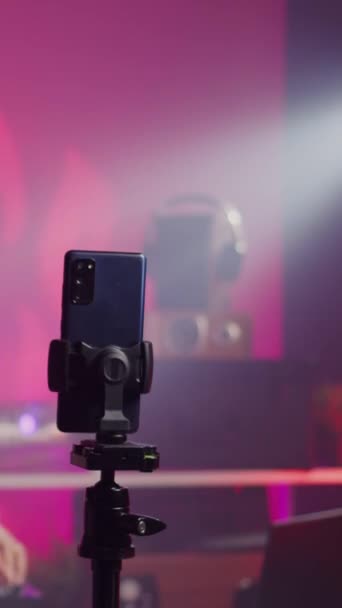 Vertical video: Aasian taiteilija sekoittamalla techno äänen tallennus musiikin istunnon älypuhelin kamera, nauttia esiintymässä elektroninen osapuoli yökerhossa. Muusikko pelaa remix käyttäen ammatillista ääntä - Materiaali, video