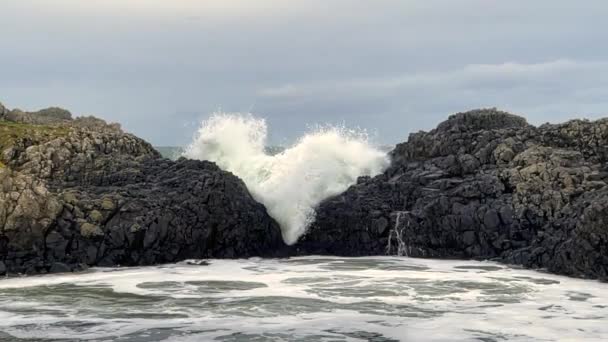 Slow motion video of wave crashing over rocks on a cold winter's day in the north coast of Ireland - Filmati, video