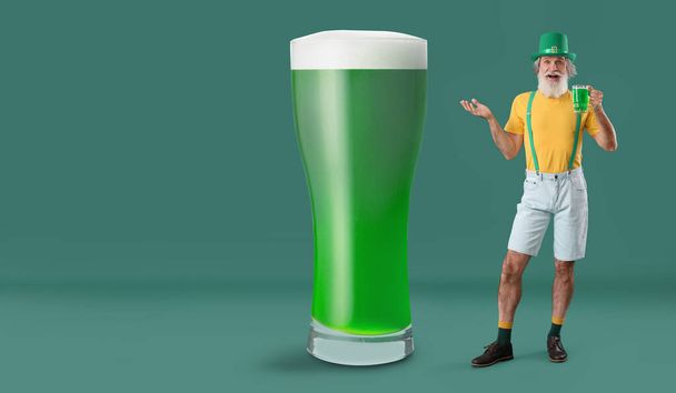 Senior man and big glass of beer on green background. St. Patrick's Day celebration - Фото, изображение