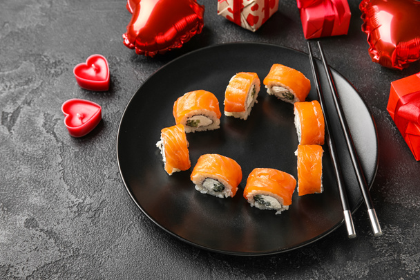 Πιάτο με σούσι ρολά, ξυλάκια και δώρα σε σκούρο φόντο, κοντινό πλάνο. Γιορτή του Αγίου Βαλεντίνου - Φωτογραφία, εικόνα