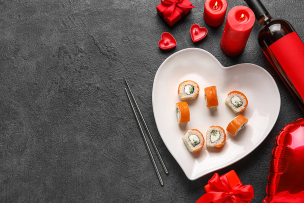 Plate with sushi rolls, candles and wine bottle on dark background. Valentine's Day celebration - Fotó, kép